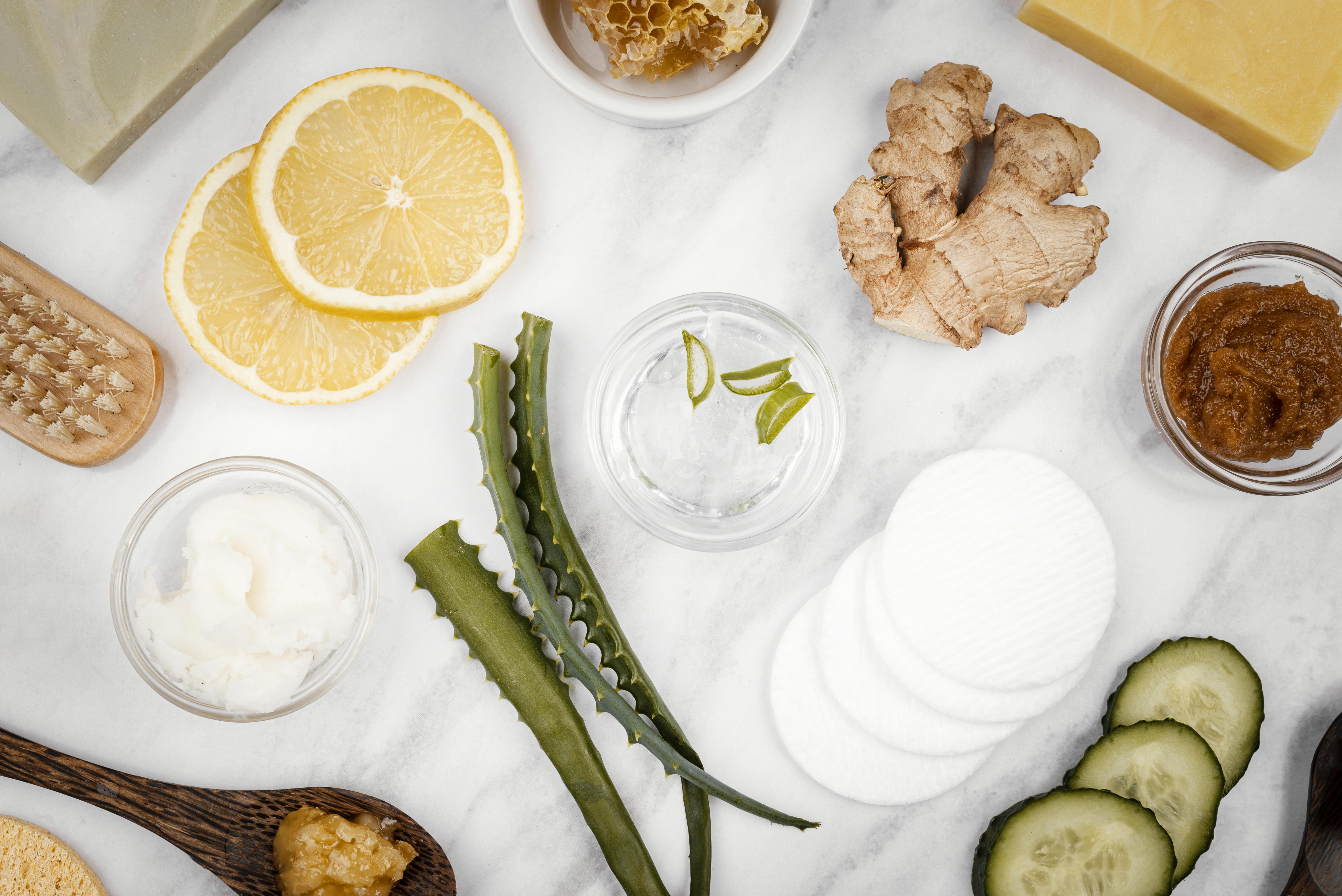 homemade-treatment-ingredients-flat-lay Natural beauty ingredients like lemon, ginger, aloe vera and honey with cotton pads, showing botanical skincare.