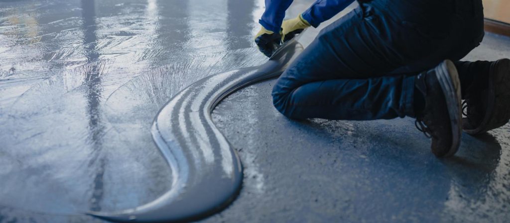 worker-applies-gray-epoxy-resin-new-floor (Custom)