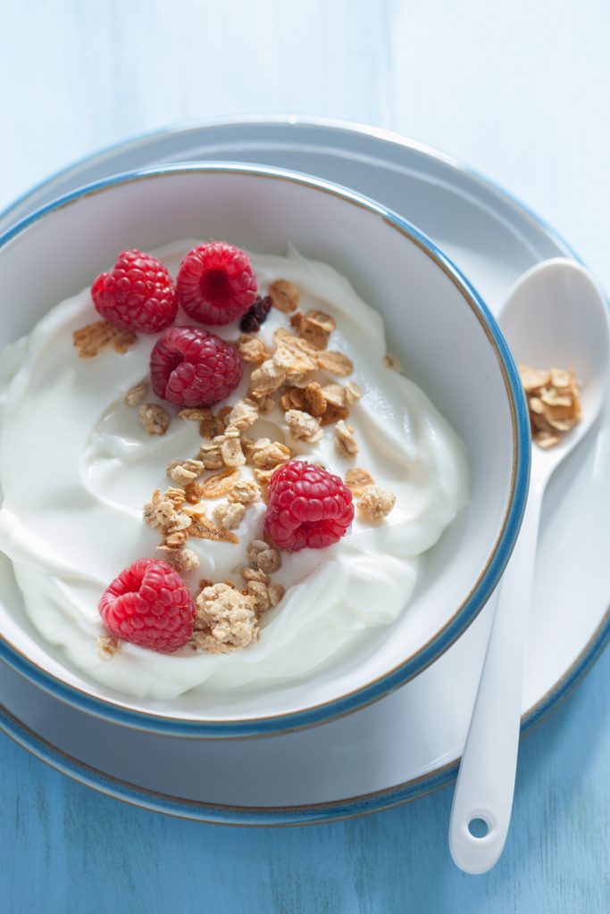 yogurt with granola and raspberry for healthy breakfast Yogurt bowl with raspberries and granola, representing gut-friendly foods that support healthy skin.